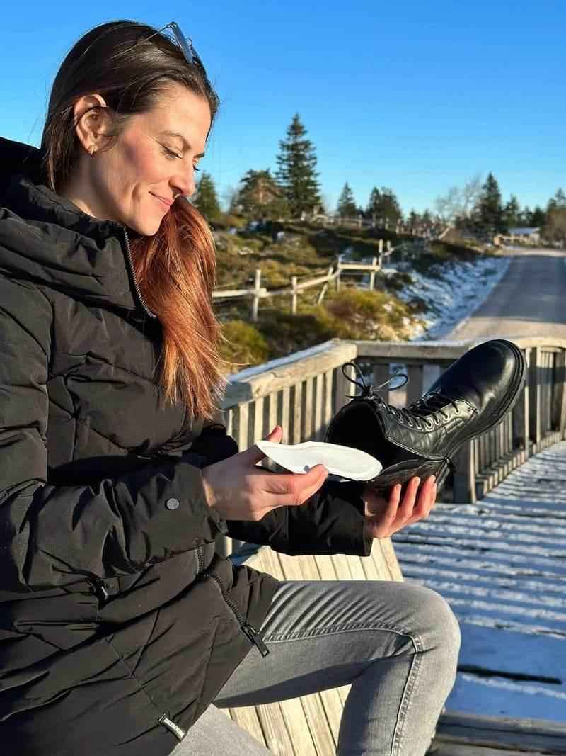 Calentador de pies blanco colocado en zapato negro